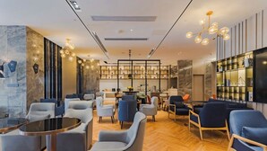 A modern lounge area with seating, a coffee table, and a bookshelf. - Echarm International Hotel Pazhou Convention and Exhibition Center Nanzhou Subway Metro Branch (Guangzhou)
