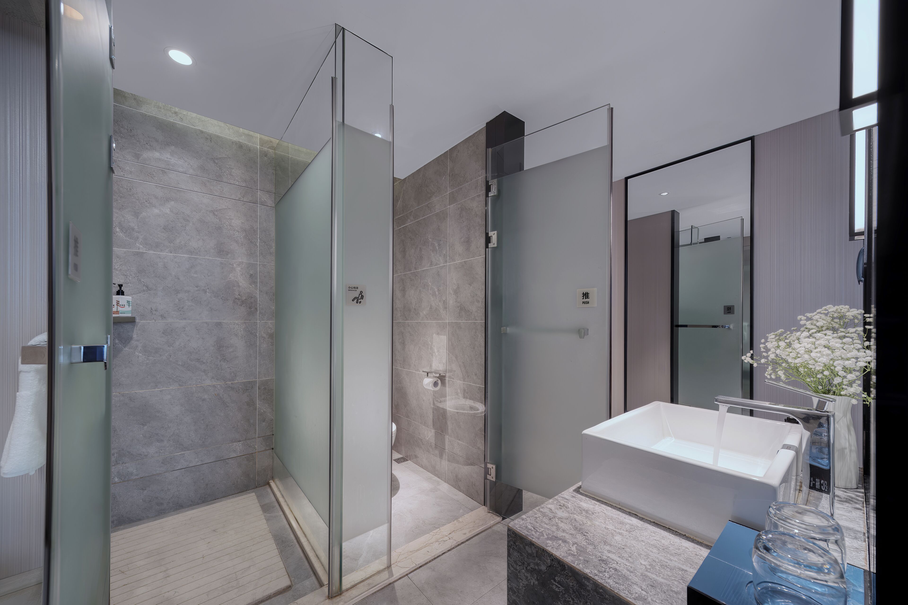 Une salle de bain moderne avec une douche à parois de verre, un lavabo blanc et un grand miroir.