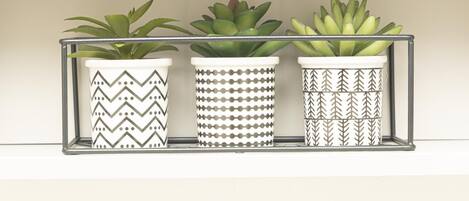Three potted plants in a metal rack with patterned pots.