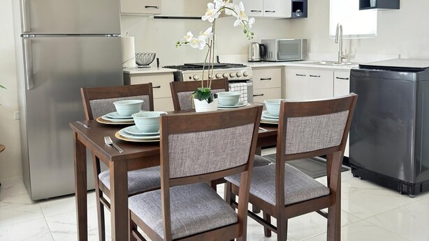 Une cuisine moderne équipée d’un four encastré, d’un réfrigérateur et d’un coin repas avec une table dressée pour quatre personnes.