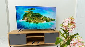 Un téléviseur posé sur un meuble TV en bois, avec une télécommande à proximité.