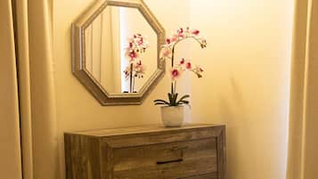 A wooden dresser with drawers, a mirror, and a potted orchid.
