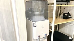 A water dispenser with a clear container, a control panel, and a water bottle holder.