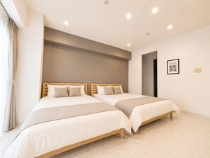 A double room with two beds, a ceiling light, a framed picture, and a door.