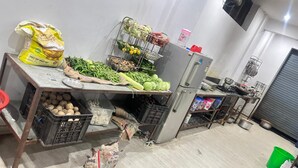 A kitchen area with a refrigerator, a sink, and various food items like vegetables and potatoes. - Hotel Hari Inn  (Jaipur)
