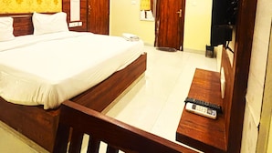 A hotel room with a bed, a desk, a chair, a TV, and an air conditioning unit. - Hotel Hari Inn  (Jaipur)