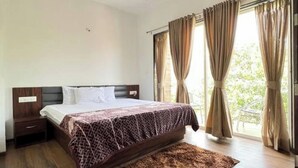 Un dormitorio con cama, mesita de noche, cabecero de madera y ventana con cortinas.
