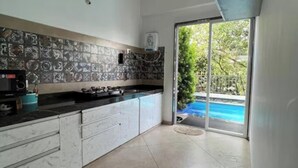 Una cocina moderna con salpicadero de azulejos, estufa a gas y vista a una piscina a través de un ventanal.