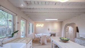A modern kitchen with a central island, white cabinetry, and a large window.