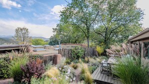 A garden with a wooden deck, various plants, and a view of distant mountains.