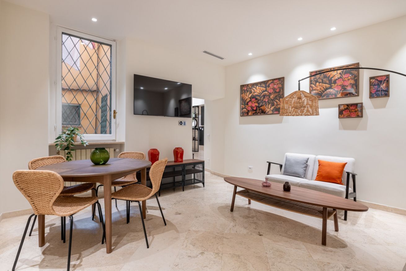 A modern living room with a dining area, a sofa, and artwork on the walls.