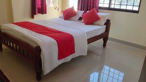 A neatly made bed with a wooden frame, white bedding, and a red blanket. - Shanthala Residency (Virajpet)