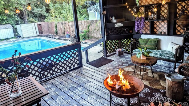 A covered outdoor area with a pool, a fire pit, and outdoor furniture.