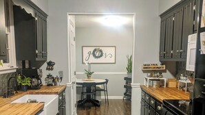 A kitchen with wooden flooring, a dining table with chairs, and a refrigerator.