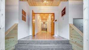 Ein modernes Interieur mit einer Holztreppe, die zu einem Flur mit Holzboden und einem Schild führt, auf dem 'Willkommen Zuhause' steht.