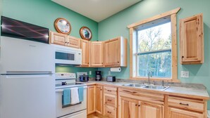 A kitchen with wooden cabinets, a white refrigerator, a microwave, a stove, and a sink. - Ultimate UP Retreat Near ATV Trails & Twin Lakes (Toivola)