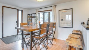 A dining area with a wooden table and chairs, a small plant, and a framed menu on the wall. - Hike, Ski & More: Walkable Downtown Granby Home (Granby)