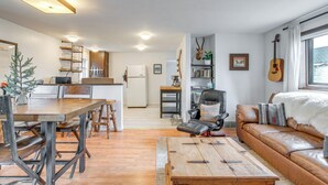 A modern living room with a wooden coffee table, leather sofa, and a dining area with a wooden table and benches. - Hike, Ski & More: Walkable Downtown Granby Home (Granby)