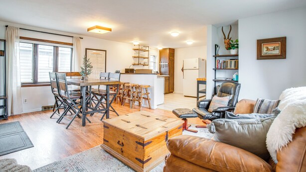 A spacious living area with a wooden dining table, leather sofa, and a kitchen in the background. - Hike, Ski & More: Walkable Downtown Granby Home (Granby)