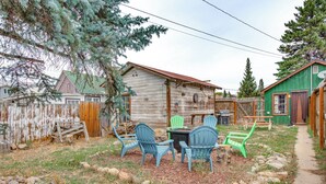A rustic wooden house with a green door, a wooden fence, and outdoor seating with chairs. - Hike, Ski & More: Walkable Downtown Granby Home (Granby)