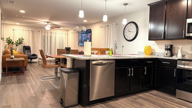 A modern kitchen with stainless steel appliances, a built-in island, and a dining area with a sofa and chairs. - Modern Riverside Home • Sleeps 8 • Near Downtown (Jacksonville)