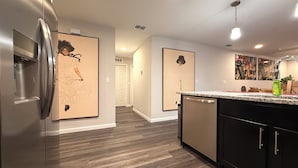 A modern kitchen with a stainless steel refrigerator, a granite countertop, and a dishwasher. - Modern Riverside Home • Sleeps 8 • Near Downtown (Jacksonville)