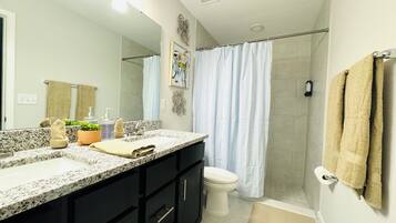 A modern bathroom with a granite countertop, black cabinets, a white toilet, and a glass shower enclosure.