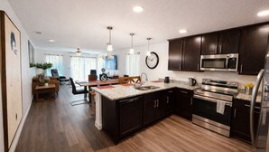 A modern kitchen with dark cabinetry, stainless steel appliances, and a central island. - Modern Riverside Home • Sleeps 8 • Near Downtown (Jacksonville)