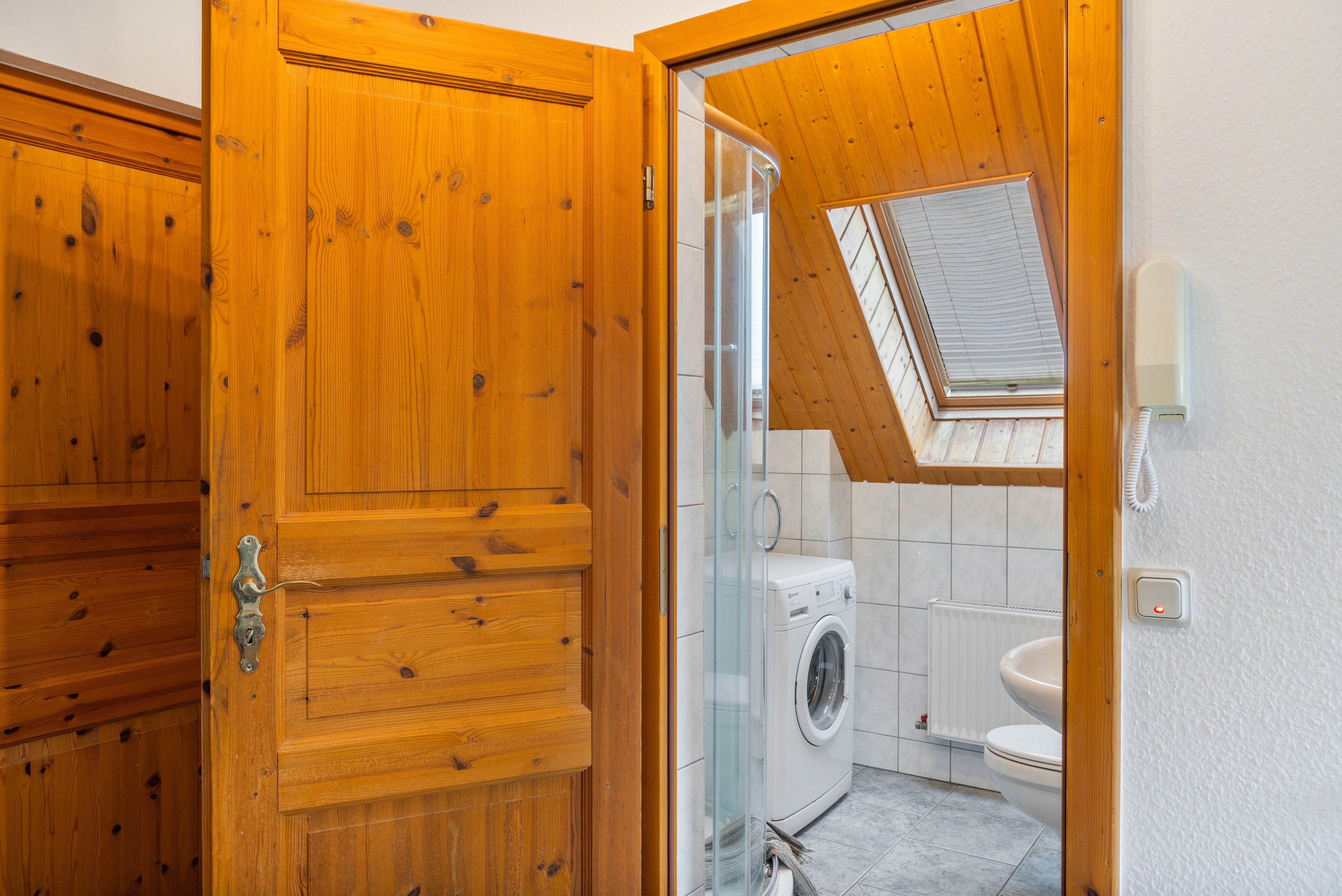 A wooden door leading to a laundry room with a washing machine and a toilet.