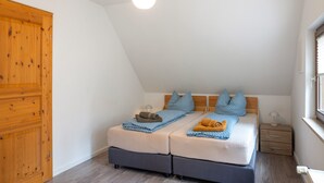 Un dormitorio con una cama doble, dos mesitas de noche, un armario de madera y una ventana con persianas.