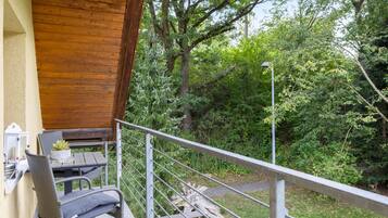 Ein Balkon mit Korbmöbeln, einem Holztisch und einem Blumentopf.