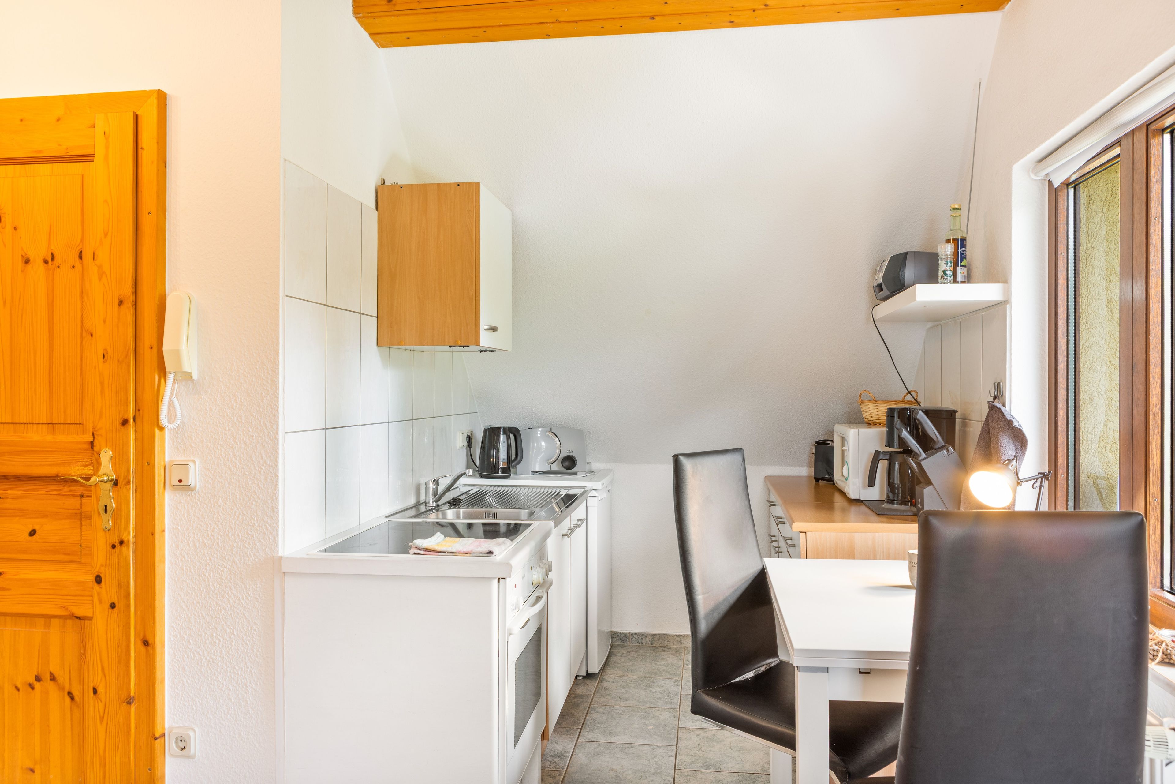 A compact kitchen with a sink, a kettle, a toaster, and a coffee maker.