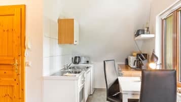 A compact kitchen with a sink, a kettle, a toaster, and a coffee maker.