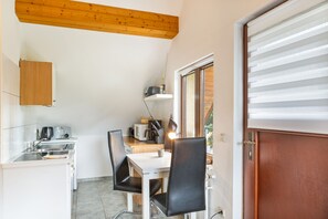 Una cocina compacta con comedor, techo de madera y ventana con persianas.