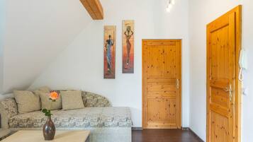Ein Wohnzimmer mit einer Couch, einer Vase mit einer Blume und zwei Bildern an der Wand.