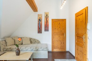 Un salon avec un canapé, un vase avec une fleur et deux tableaux accrochés au mur.