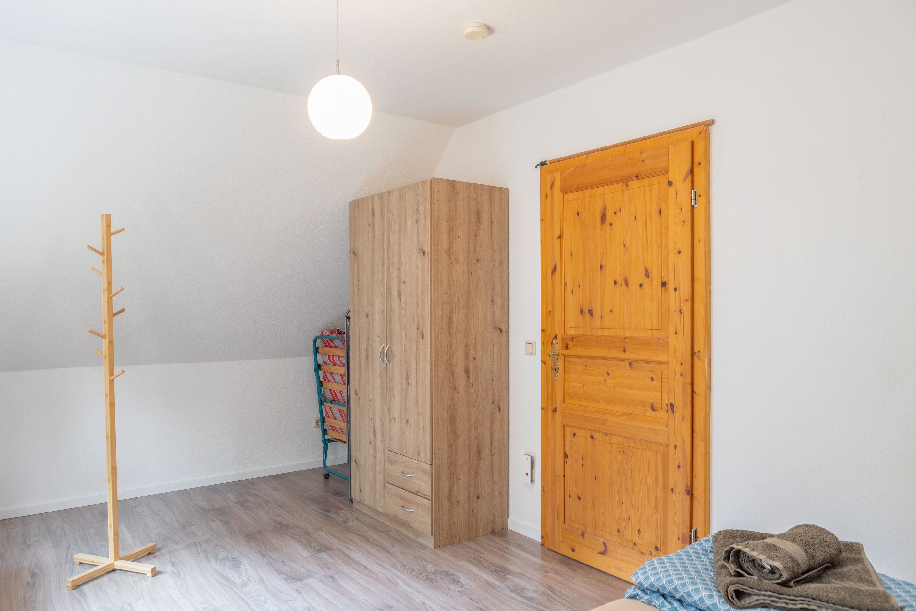 Ein Zimmer mit einem Holzschrank, einem Kleiderhaken und einer Tür.