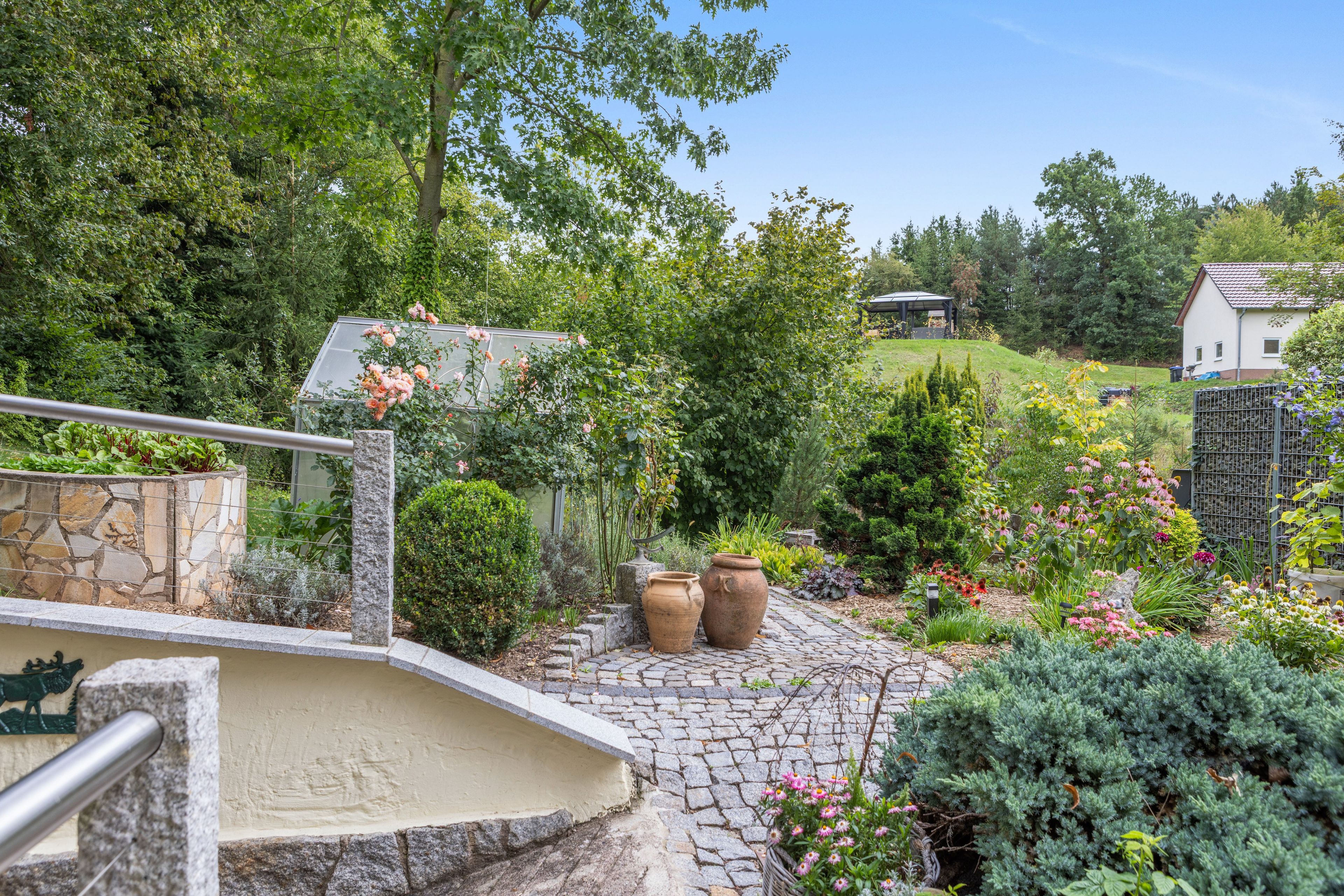 Ein Garten mit einem gepflasterten Weg, der zu einem Haus mit Schindeldach führt.