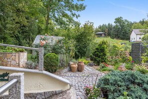 Un jardin avec un chemin de pierres menant à une maison dont le toit est en pente.