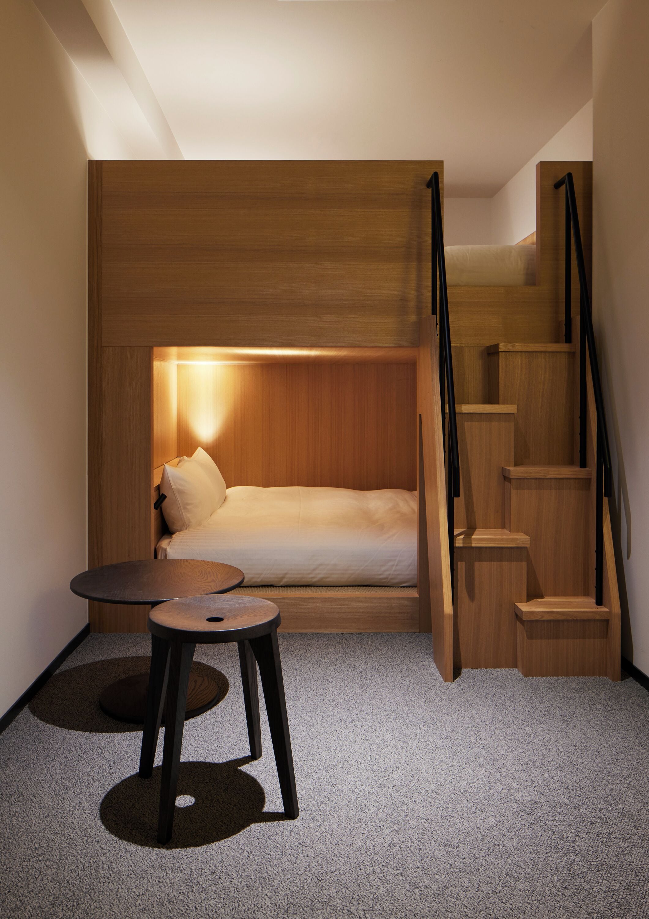 Un dormitorio pequeño con cama, una mesita y una escalera.