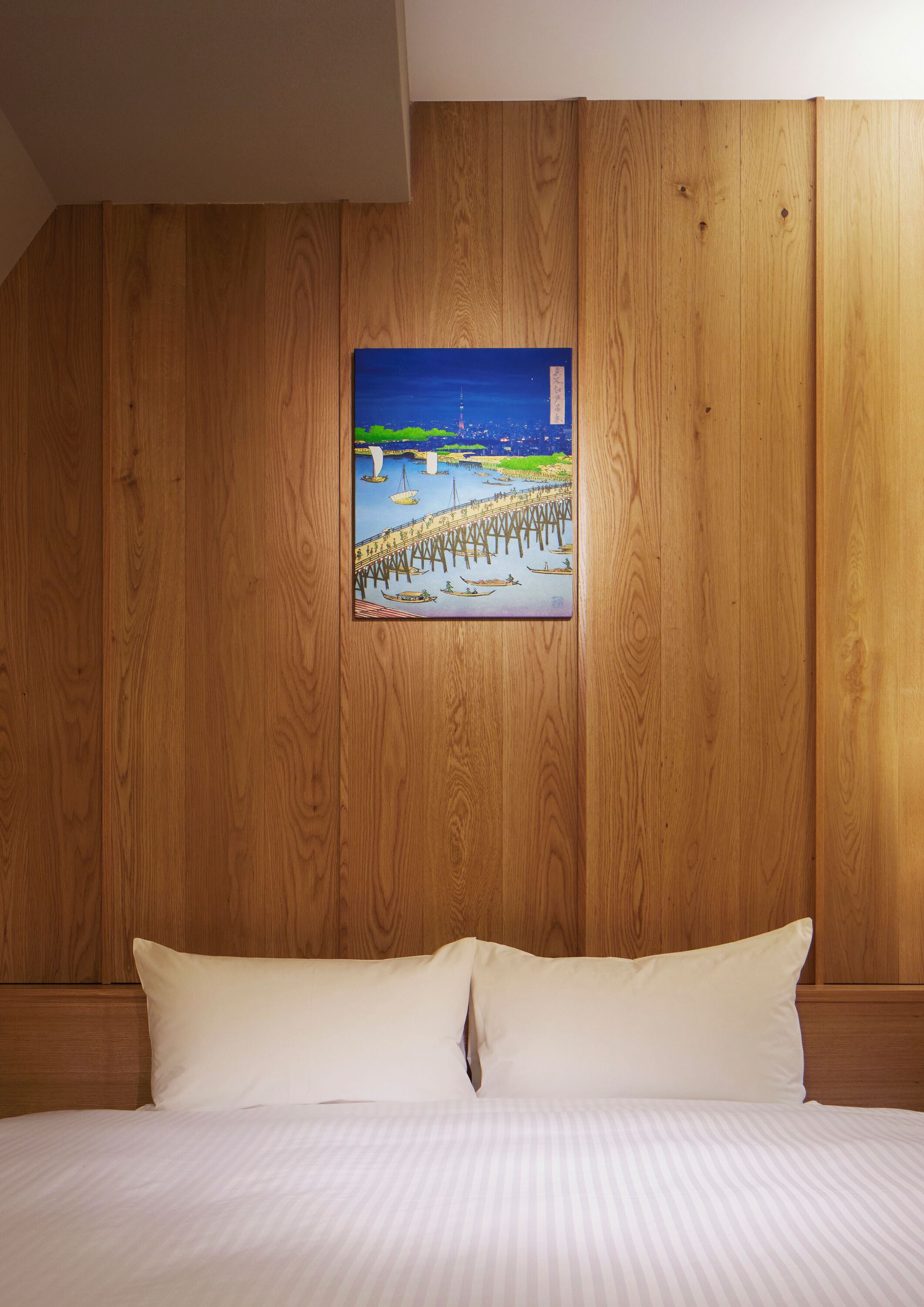 A wooden-paneled wall with a framed painting of a pier and boats.