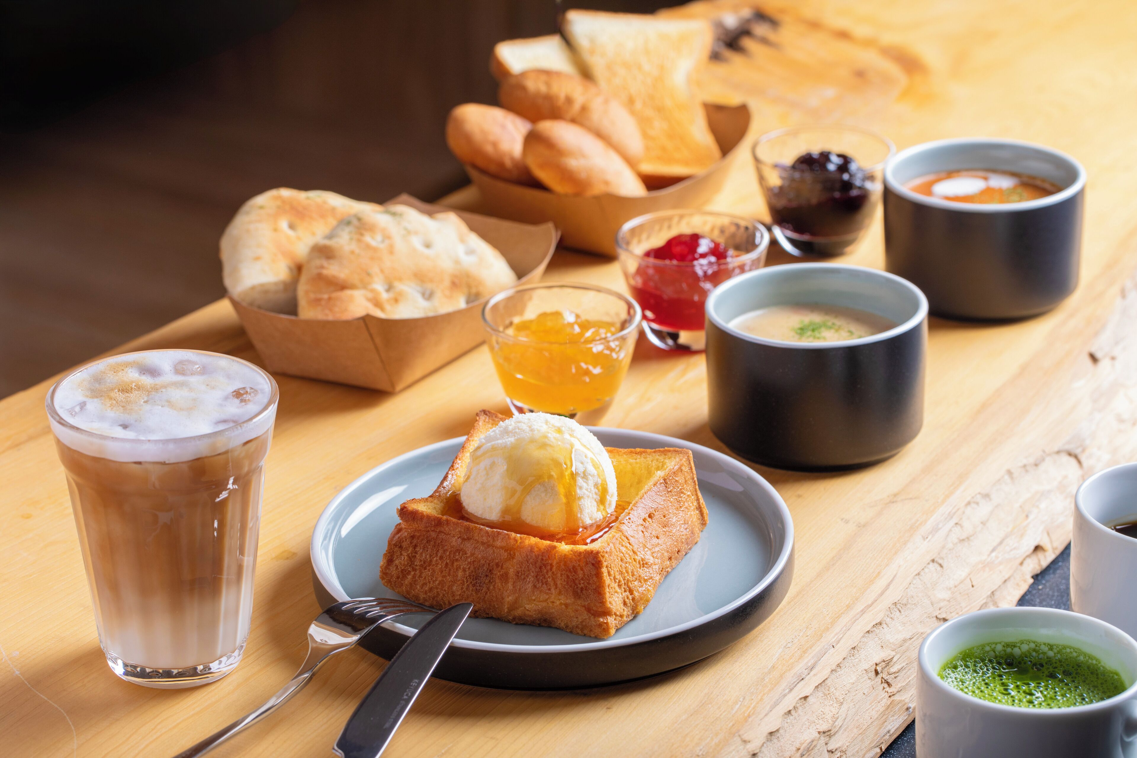 A breakfast setting with toast, jam, butter, and tea.