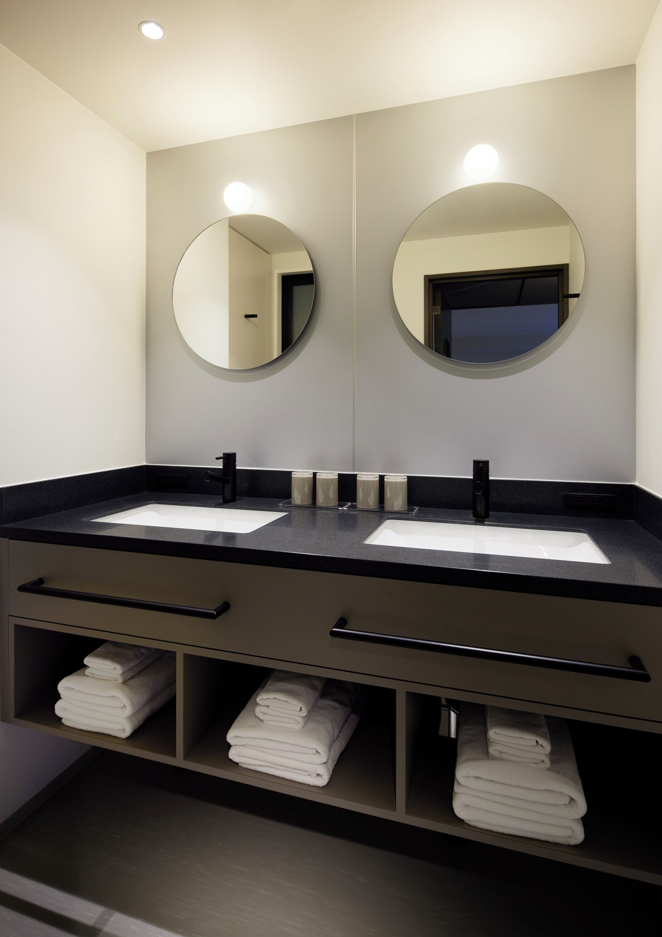 Ein modernes Badezimmer mit zwei Waschbecken, einem großen Spiegel und einem Handtuchhalter.