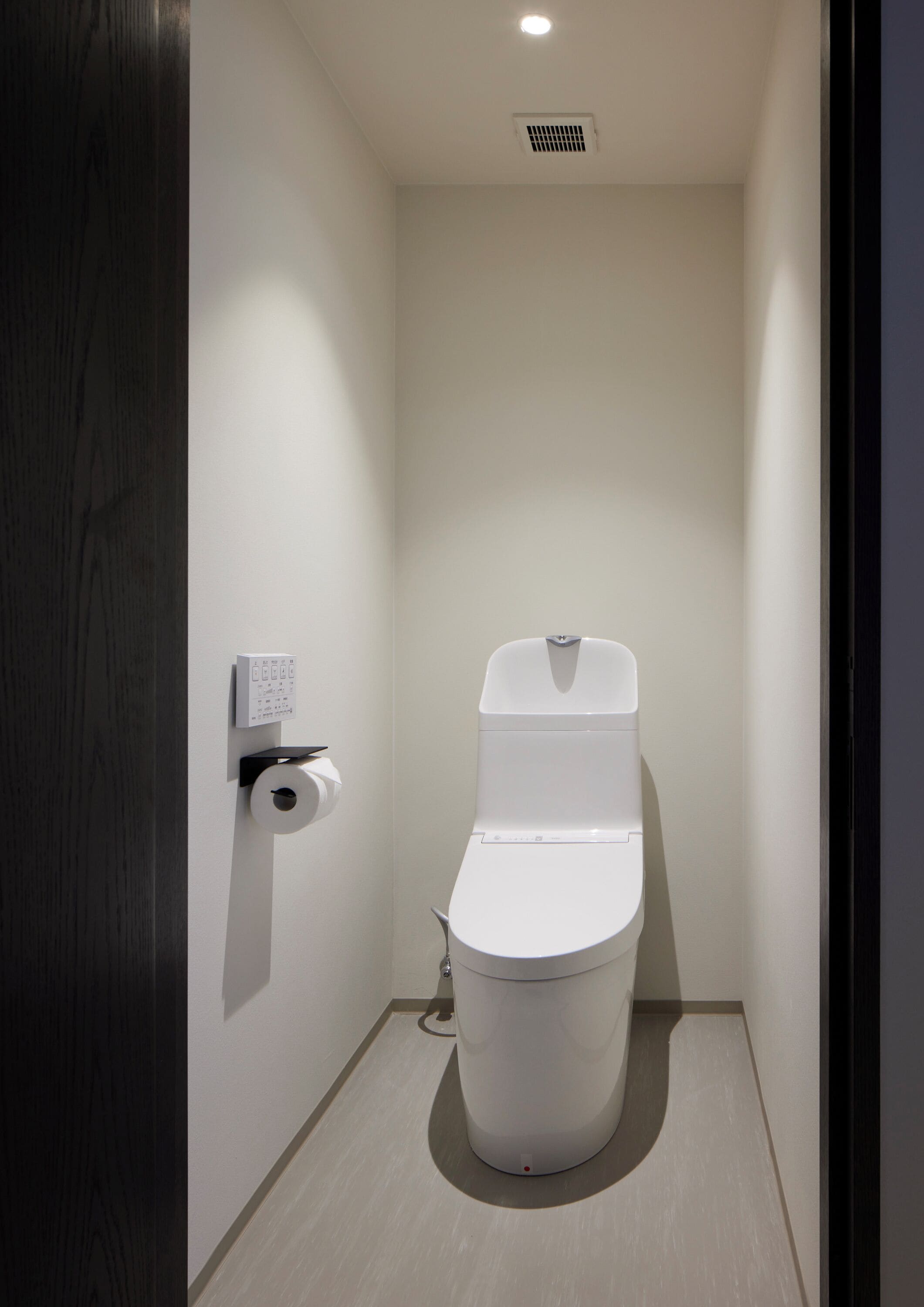 Moderni ja pienikokoinen kylpyhuone, jossa on wc, käsienkuivaaja ja paperipyyhkeiden annostelija.