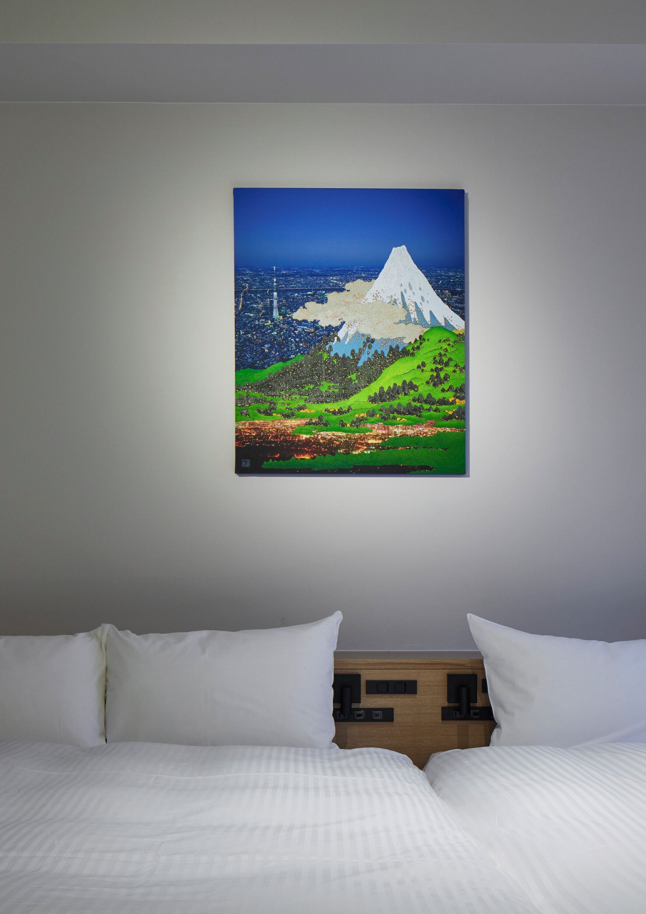 Une chambre d’hôtel avec un lit, des oreillers et un tableau représentant un paysage de montagne accroché au mur.