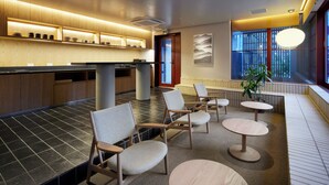 A modern hotel lobby with a reception desk, seating area, and large windows.