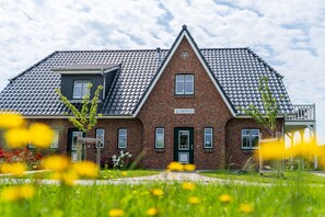 A two-story brick house with a tiled roof, a green door, and a small window. - Apartment 'Ferienhaushlfte Inselglück' with Garden and Wi-Fi (Pellworm)