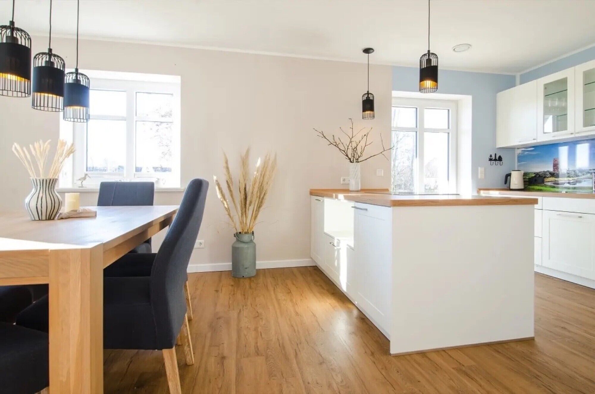 A modern kitchen with white cabinets, a wooden island, and pendant lighting.