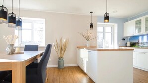 A modern kitchen with white cabinets, a wooden island, and pendant lighting.