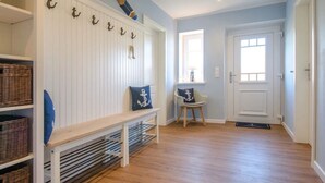 A hallway with a wooden bench, a chair, and a door.